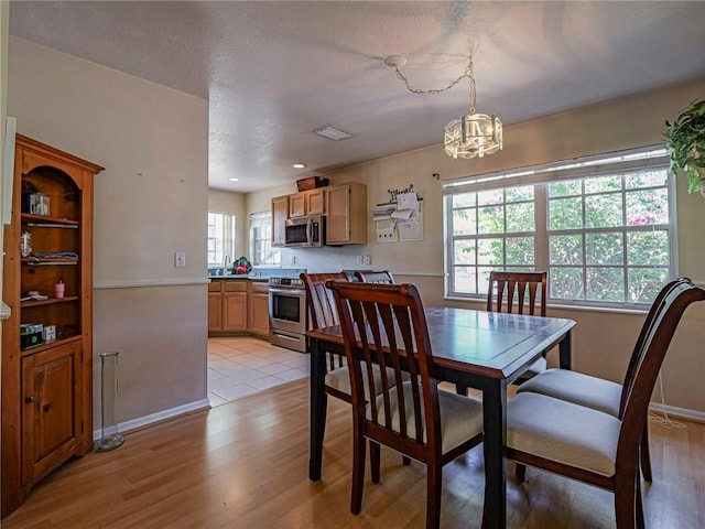 dining space with light wood-style flooring, visible vents, and baseboards