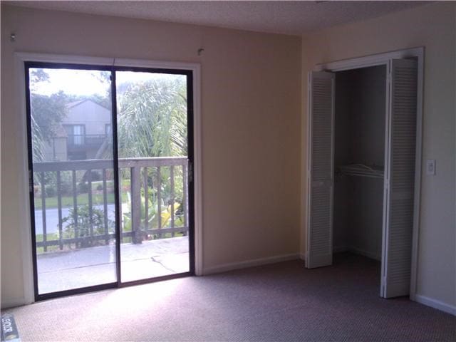 unfurnished bedroom with multiple windows, a closet, carpet, and access to outside