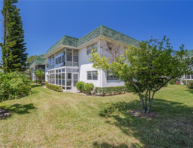 view of side of property with a sunroom and a yard