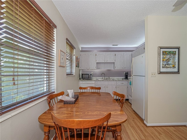 dining area with sink, light hardwood / wood-style floors, and a textured ceiling