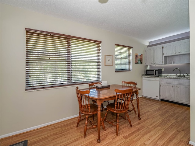 dining area featuring a textured ceiling, sink, and light wood-type flooring