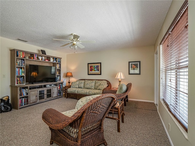 carpeted living room featuring ceiling fan and a textured ceiling