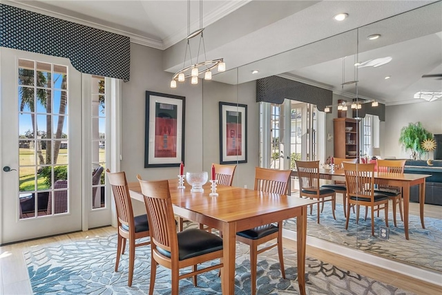 dining space featuring crown molding, light hardwood / wood-style floors, and vaulted ceiling