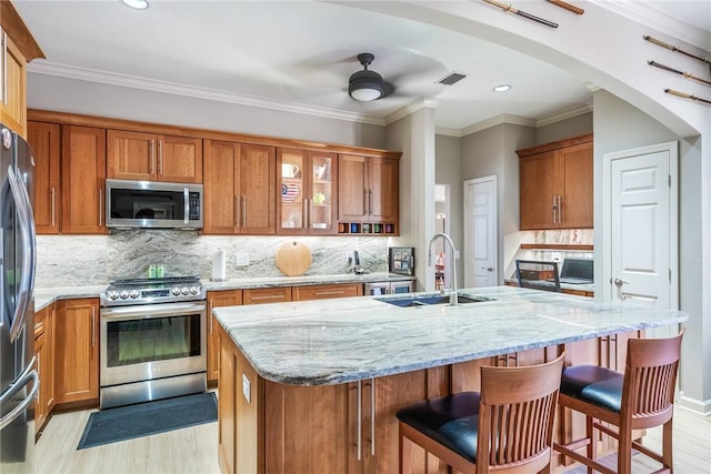 kitchen with light stone counters, a kitchen bar, sink, and appliances with stainless steel finishes