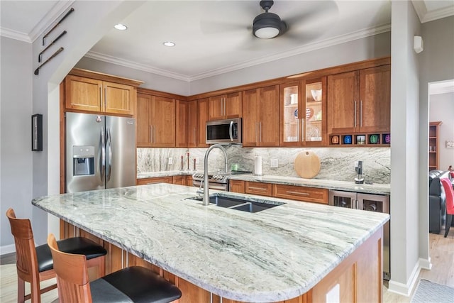 kitchen featuring a breakfast bar, sink, light stone counters, a center island with sink, and stainless steel appliances