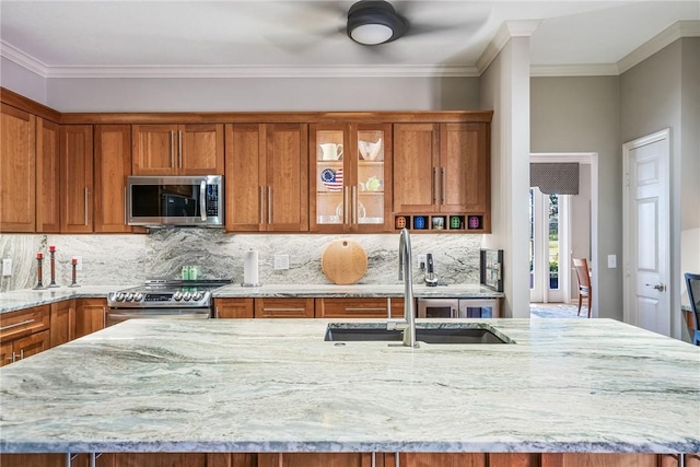 kitchen featuring sink, stainless steel appliances, light stone counters, an island with sink, and decorative backsplash