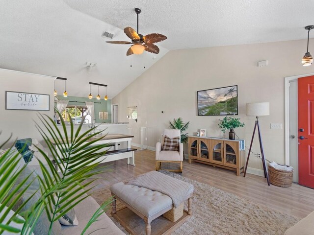 living area with wood finished floors, visible vents, a ceiling fan, baseboards, and high vaulted ceiling