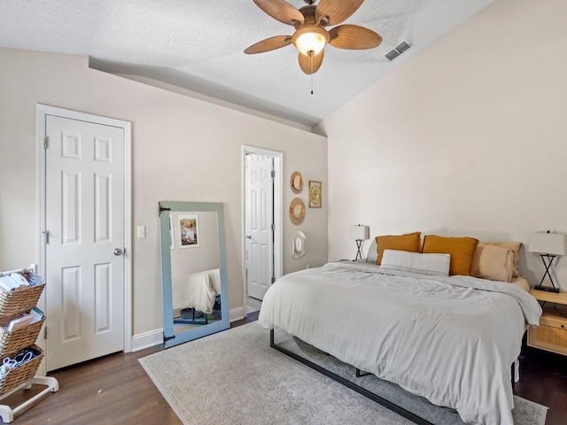 bedroom featuring wood finished floors, a textured ceiling, ceiling fan, baseboards, and visible vents