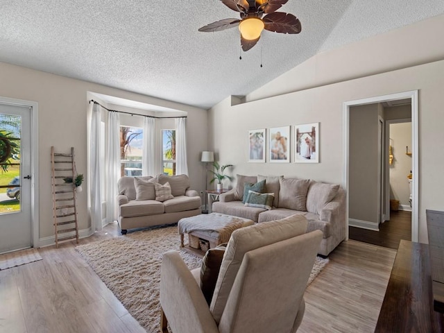living area with lofted ceiling, a ceiling fan, a textured ceiling, and light wood finished floors