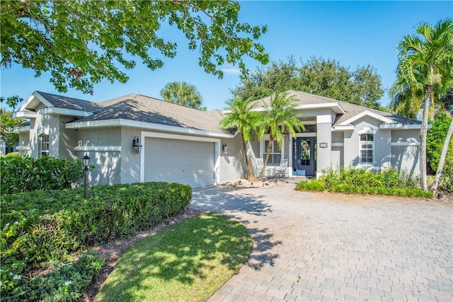 single story home featuring a garage, decorative driveway, and stucco siding