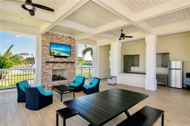 view of patio / terrace with a deck, ceiling fan, and an outdoor living space with a fireplace