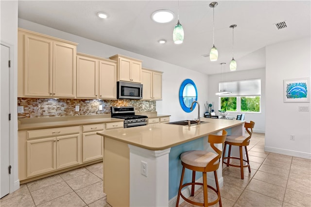 kitchen with stainless steel appliances, a center island with sink, sink, a kitchen breakfast bar, and pendant lighting