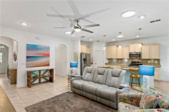 tiled living room with sink, ceiling fan, and a textured ceiling