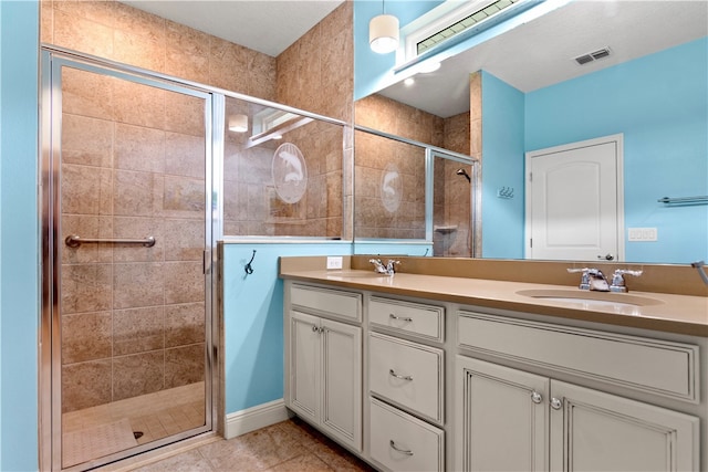 bathroom with an enclosed shower, vanity, and tile patterned flooring