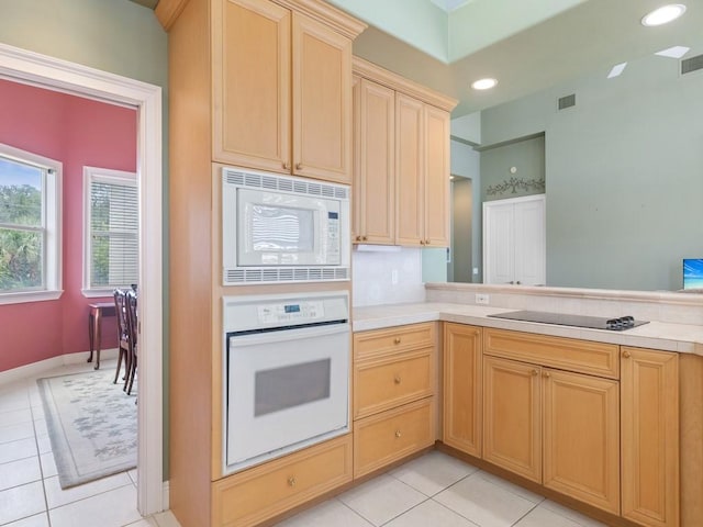 kitchen featuring kitchen peninsula, light brown cabinetry, light tile patterned floors, and white appliances