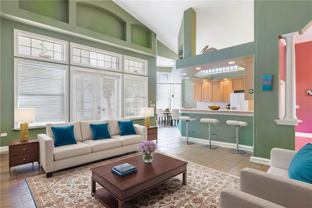 living room featuring decorative columns, high vaulted ceiling, and light tile patterned floors