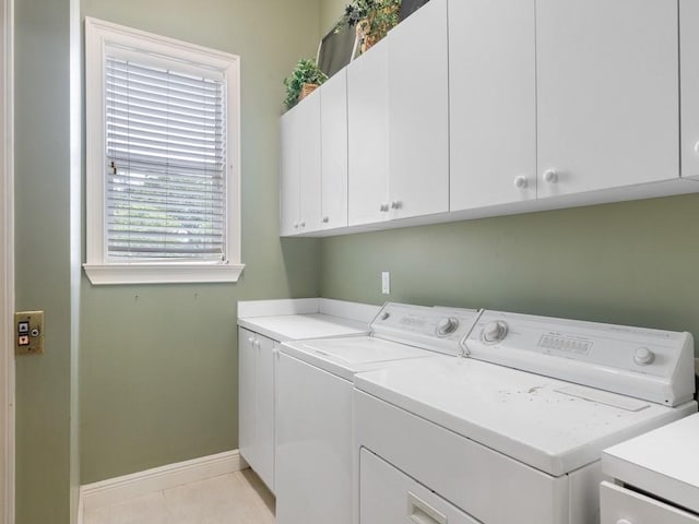 laundry room featuring separate washer and dryer, light tile patterned floors, and cabinets