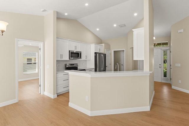 1590 Polynesian Ln, Sebastian, FL 32958 - kitchen with appliances with stainless steel finishes, white cabinets, light wood-style flooring, decorative backsplash, and a peninsula
