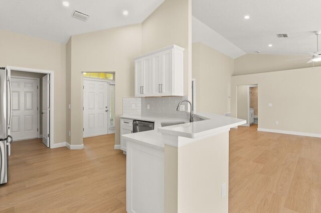 1590 Polynesian Ln, Sebastian, FL 32958 - kitchen featuring white cabinetry, light wood finished floors, light countertops, vaulted ceiling, and tasteful backsplash