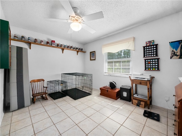 misc room with a textured ceiling, ceiling fan, and light tile patterned floors