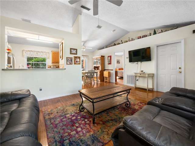 living room with hardwood / wood-style flooring, ceiling fan, and vaulted ceiling