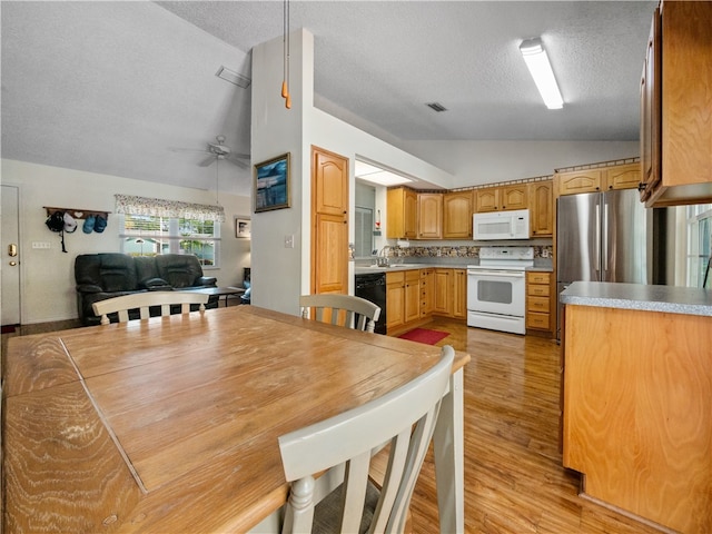 kitchen with vaulted ceiling, a textured ceiling, ceiling fan, light hardwood / wood-style flooring, and white appliances