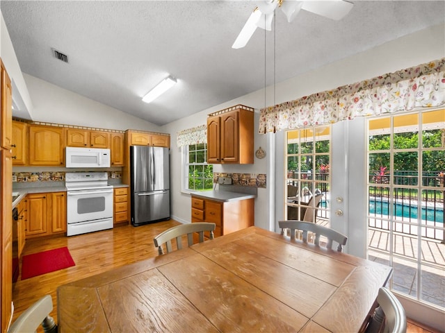 kitchen with white appliances, plenty of natural light, light wood-type flooring, and lofted ceiling