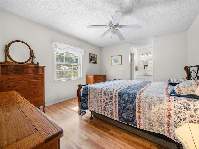 bedroom with a textured ceiling, light hardwood / wood-style floors, ceiling fan, and connected bathroom