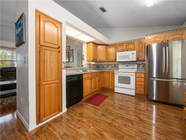 kitchen featuring sink, a textured ceiling, white appliances, dark hardwood / wood-style flooring, and vaulted ceiling