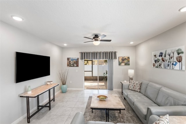 living room with ceiling fan, light tile patterned floors, and a textured ceiling