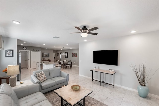 tiled living room featuring ceiling fan and sink