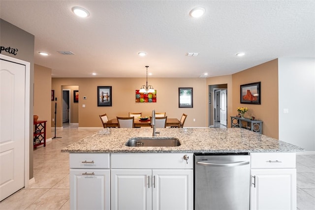 kitchen featuring stainless steel dishwasher, sink, decorative light fixtures, white cabinets, and an island with sink