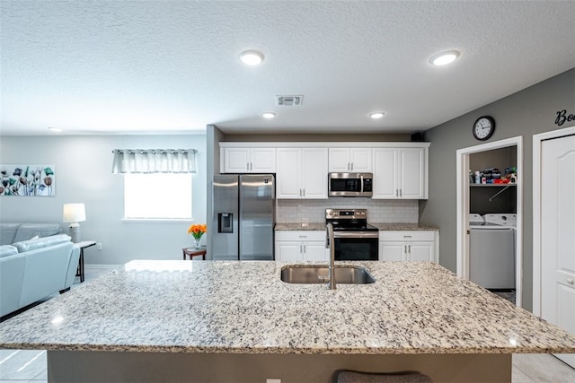 kitchen with sink, stainless steel appliances, tasteful backsplash, a kitchen island with sink, and white cabinets