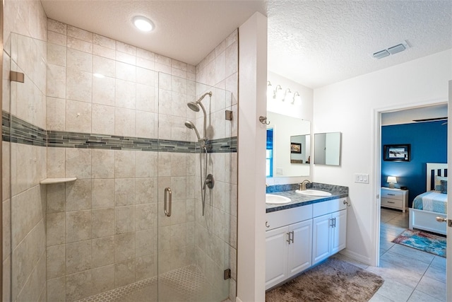 bathroom featuring tile patterned floors, vanity, a shower with door, and a textured ceiling