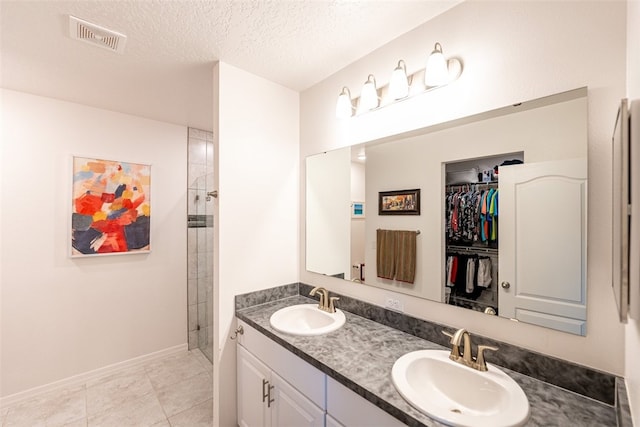 bathroom featuring a shower, vanity, a textured ceiling, and tile patterned flooring