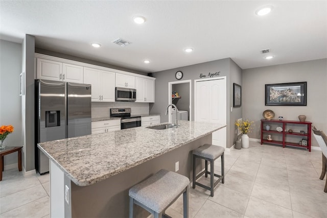 kitchen with sink, stainless steel appliances, a kitchen island with sink, and a breakfast bar area