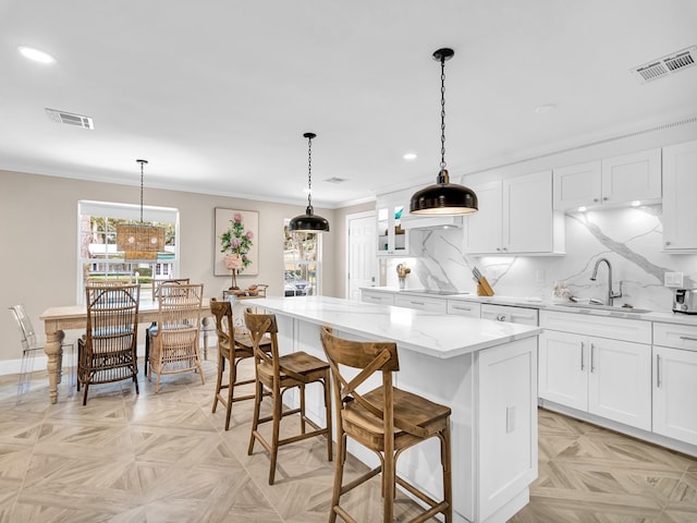 kitchen with a center island, sink, hanging light fixtures, and white cabinets