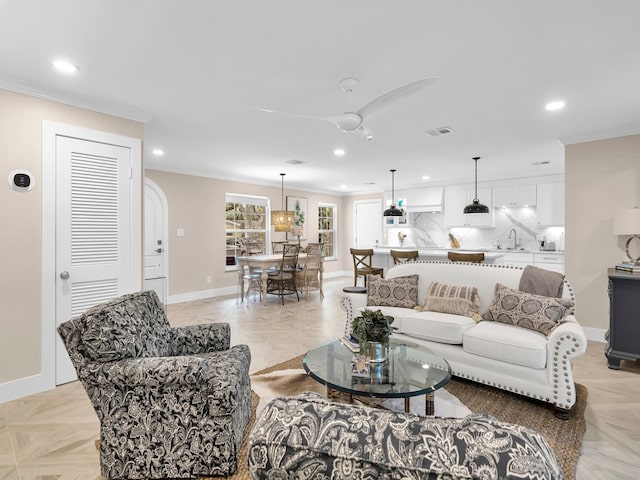 living room with sink, crown molding, light parquet floors, and ceiling fan