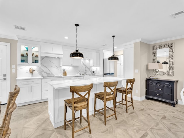 kitchen featuring white cabinetry, hanging light fixtures, a center island, and light parquet flooring