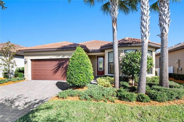 mediterranean / spanish house with decorative driveway, an attached garage, and stucco siding