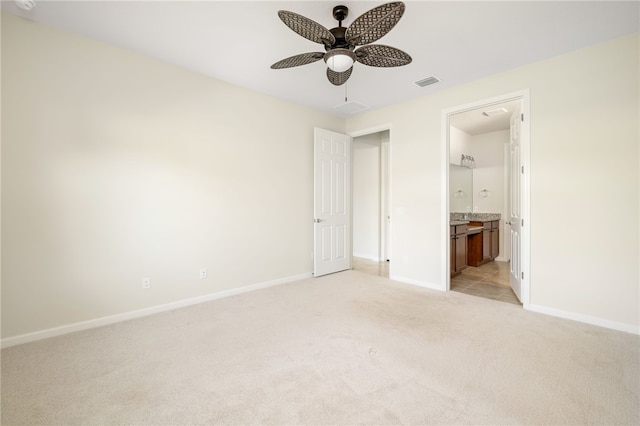 unfurnished bedroom featuring ceiling fan, ensuite bathroom, light colored carpet, visible vents, and baseboards