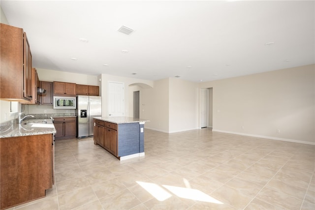 kitchen with brown cabinetry, a kitchen island, stainless steel appliances, and open floor plan