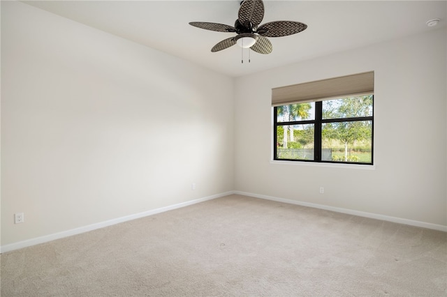 carpeted empty room with a ceiling fan and baseboards