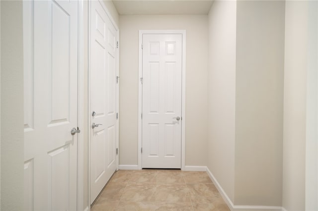 corridor with baseboards and light tile patterned floors