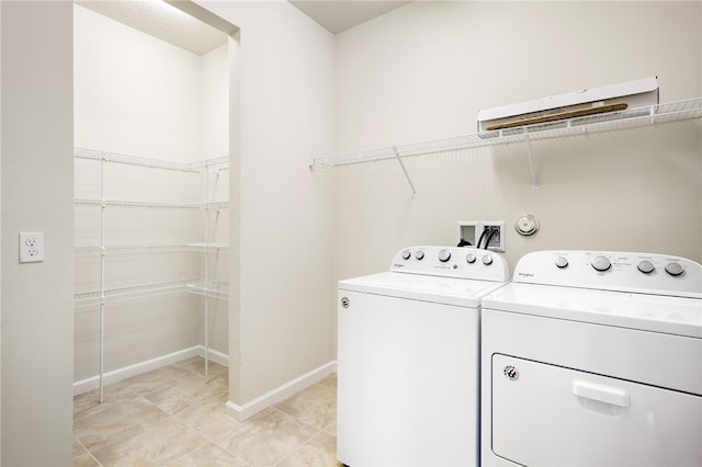 clothes washing area with laundry area, light tile patterned flooring, washing machine and dryer, and baseboards