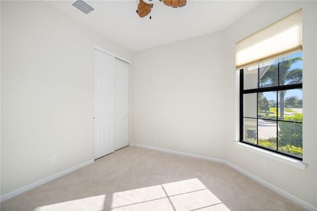 spare room featuring baseboards, visible vents, a ceiling fan, and light colored carpet