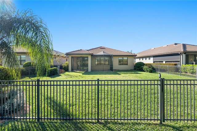 view of front of house featuring a fenced backyard, a tile roof, a sunroom, stucco siding, and a front lawn