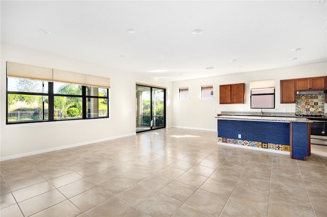 unfurnished living room with light tile patterned floors, a sink, and baseboards