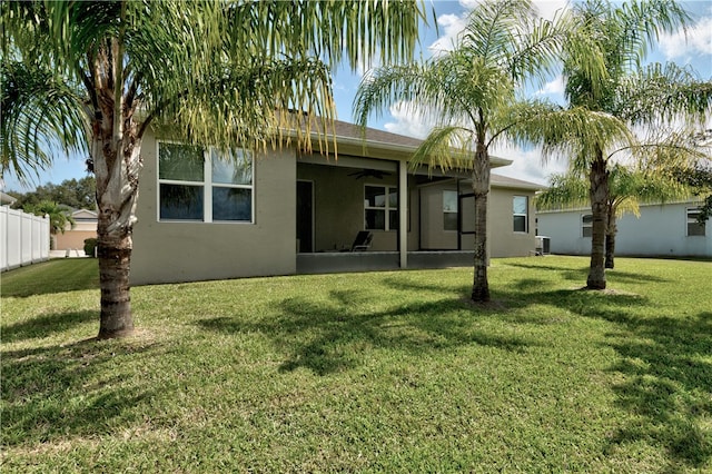 rear view of house with central AC, a lawn, and ceiling fan