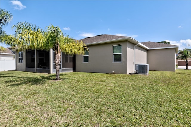 back of property with a sunroom, central AC unit, and a lawn